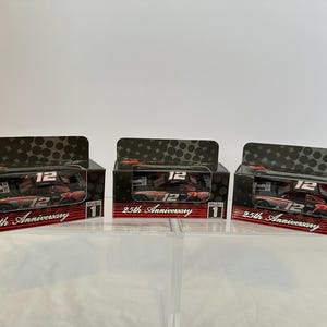 May include: Three black boxes with red and white accents. Each box features a miniature race car with the number 12 on it. The boxes are labeled "25th Anniversary" and "Mobil 1".