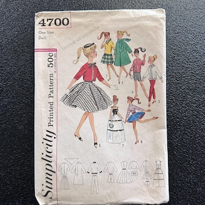 May include: Vintage Simplicity printed pattern for a doll, featuring illustrations of various doll outfits. The pattern cover displays a retro design with the number 4700 and the text "One Size Doll". The price is marked as 50c in Canada.
