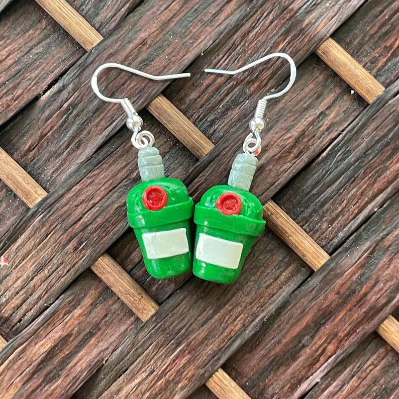 May include: A pair of green bottle-shaped earrings with red tops and silver hooks.