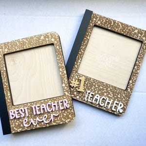 May include: Two wooden picture frames with a notebook paper design. The frames have a black border and a cutout for a photo. One frame says "Best Teacher Ever" and the other says "#1 Teacher".