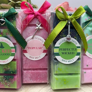 May include: Four wax melt bars in clear packaging, each with a different colour scheme and scent. The bars are decorated with ribbons and charms. Each package has a label with the words "Wicked Scents" and a unique phrase like "Popular".