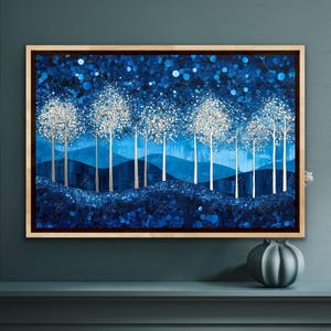 May include: A framed abstract art piece featuring a forest scene in shades of blue. The artwork depicts white trees with silver trunks against a dark blue background with a textured appearance. The frame is a light brown color.