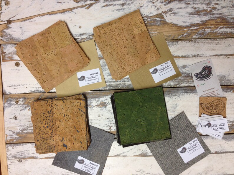 May include: Assortment of cork fabric samples in various colors and textures, including natural cork, green cork, and brown cork. The samples are labeled with "Backing" and the type of cork. There are also small cards with the word "FOLICLORE" printed on them.