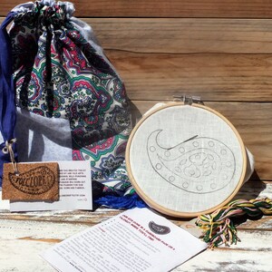 May include: A paisley embroidery kit with a wooden embroidery hoop, a piece of fabric with a paisley design, embroidery floss, and instructions. The kit comes in a blue and white paisley drawstring bag.