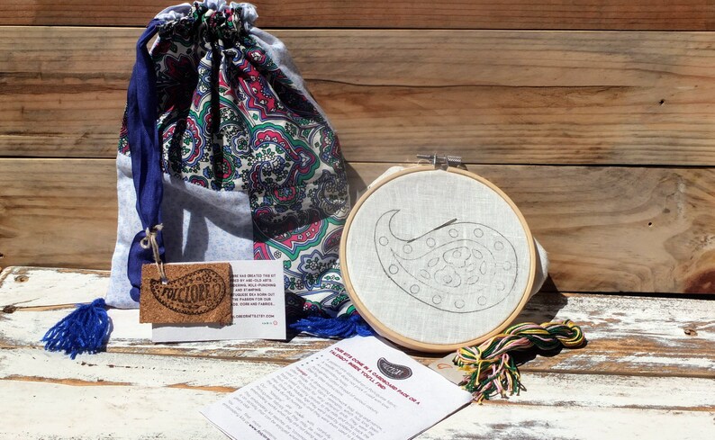 May include: A paisley embroidery kit with a wooden embroidery hoop, a piece of fabric with a paisley design, embroidery floss, and instructions. The kit comes in a blue and white paisley drawstring bag.