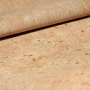 Pode incluir: Um close-up de uma folha de tecido de corti&ccedil;a natural de cor castanho claro e com um padr&atilde;o salpicado.