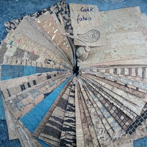 May include: A fan-shaped display of various cork fabric samples in different colors, patterns, and textures. The samples are arranged in a circle with a label that reads "Cork Fabric".