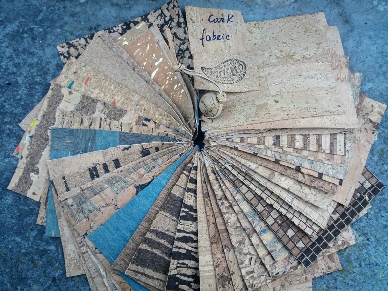 May include: A fan-shaped display of various cork fabric samples in different colors, patterns, and textures. The samples are arranged in a circle with a label that reads "Cork Fabric".