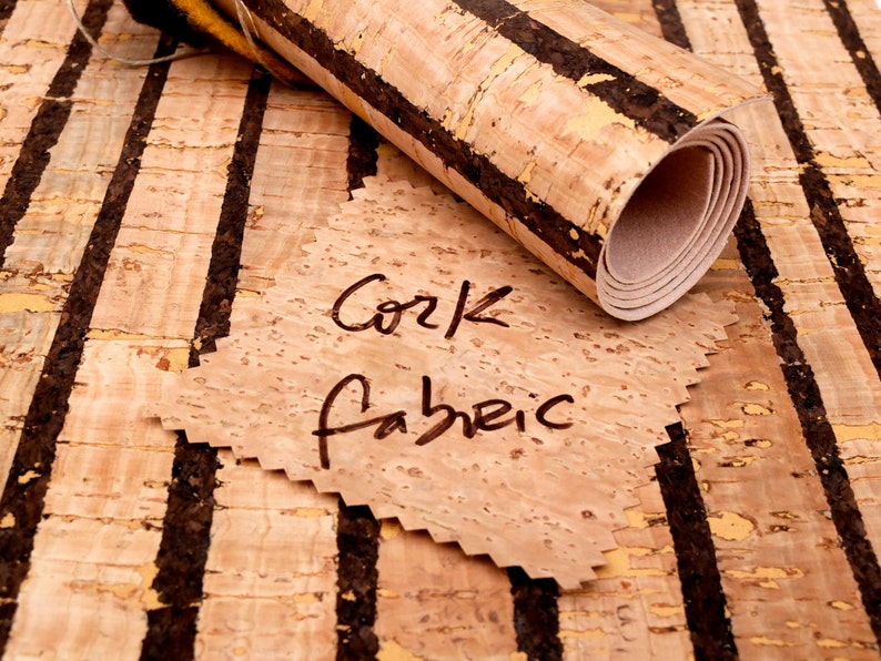 May include: A roll of cork fabric with black stripes. The fabric is rolled up and the label says "Cork Fabric".