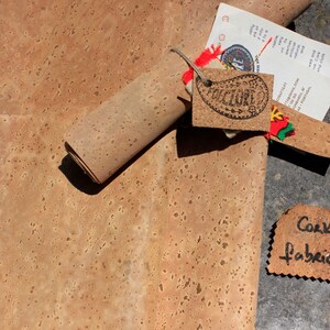 Pode incluir: Um rolo de tecido de corti&ccedil;a, desenrolado para mostrar a textura. O tecido &eacute; de cor castanho claro com um padr&atilde;o salpicado. Uma etiqueta com a palavra "CULTURE" est&aacute; presa ao rolo.