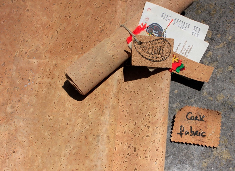 Pode incluir: Um rolo de tecido de corti&ccedil;a, desenrolado para mostrar a textura. O tecido &eacute; de cor castanho claro com um padr&atilde;o salpicado. Uma etiqueta com a palavra "CULTURE" est&aacute; presa ao rolo.