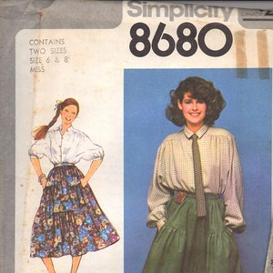 May include: Simplicity sewing pattern number 8680 for a skirt and blouse. The pattern includes two sizes, 6 and 8, for misses. The image shows two models wearing the skirt and blouse. The model on the left is wearing a floral print skirt and a white blouse. The model on the right is wearing a green skirt and a plaid blouse with a tie.