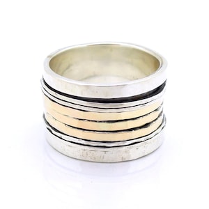May include: A silver and gold ring with multiple bands stacked on top of each other. The ring is wide and has a hammered texture.