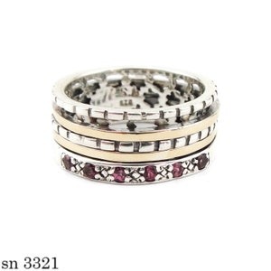 May include: A silver ring with a gold band and purple gemstones. The ring is made of multiple bands that spin around each other.