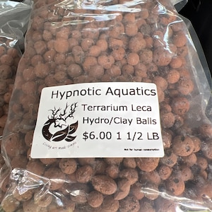 May include: A transparent bag filled with brown Hydro/Clay Balls for terrariums. The label says "Hypnotic Aquatics Terrarium Leca Hydro/Clay Balls". The bag contains approximately 0.68 kg of product.