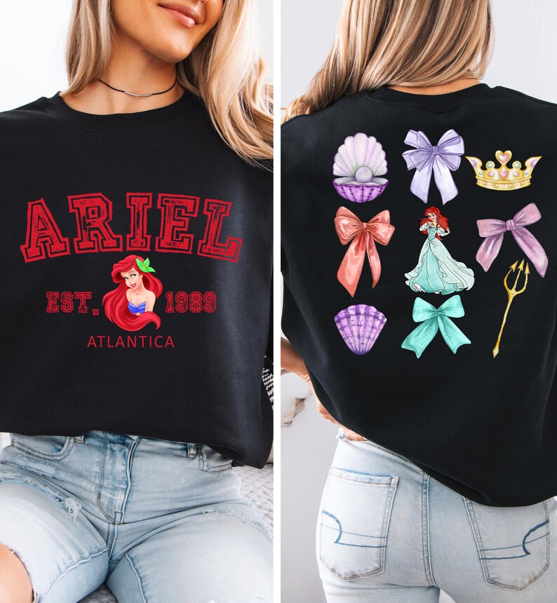 Disney Ariel sweatshirt in pastel blue with bold red varsity lettering on the front, reading 'Ariel Est. 1989 Atlantica.' The back design includes princess elements like seashells, bows, a golden trident, and an elegant illustration of