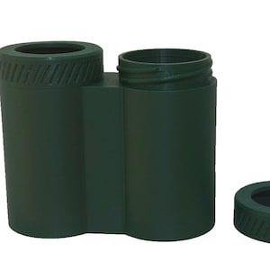 May include: A dark green, dual-chamber container with a screw-top opening and a separate, matching lid. The container has a cylindrical shape with a textured band around the top and bottom of the lid.
