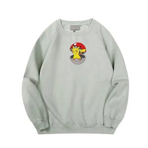 May include: A light green crew neck sweatshirt with a cartoon image of Pikachu inside a Pokeball.