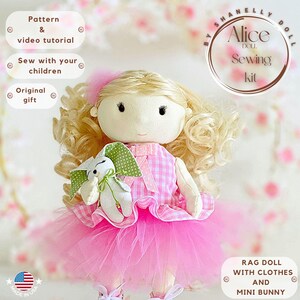 Könnte beinhalten: Ein rosa-weißes Stoffpuppen-Nähset mit einer blonden Perücke, einem rosa karierten Kleid und einem rosa Tüllrock. Die Puppe hält ein weißes Häschen mit grünen Ohren. Das Set enthält ein Schnittmuster und ein Video-Tutorial. "By Shanelly Doll Alice Sewing Kit" steht auf einem Kreis in der oberen rechten Ecke des Bildes.
