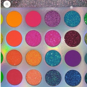 May include: A makeup eyeshadow palette featuring a grid of circular pans filled with highly pigmented powders in vibrant shades of orange, pink, purple, and blue, including both matte finishes and intense glitter textures on a holographic base.