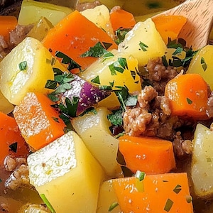 May include: A close-up of a pot of stew with ground meat, potatoes, carrots, and herbs. The stew is simmering in a brown pot with a wooden spoon.