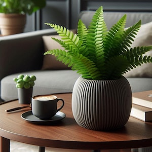May include: A gray ceramic planter with a ribbed texture holds a green fern plant. The planter is sitting on a wooden table next to a cup of coffee.