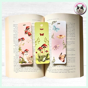 May include: Three decorative bookmarks with nature-inspired designs. One shows an owl, toadstools, and text, another a frog and toadstools, and the last one butterflies and moths. The bookmarks are placed in an open book.