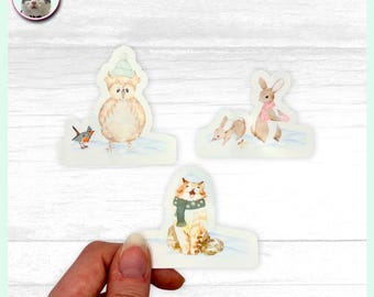 Op de afbeelding: Waterverfstickers met winterdieren: een uil met een hoed, een konijn met een roze sjaal en een kat met een groene sjaal. De stickers staan op een witte achtergrond met een lichtblauwe rand.