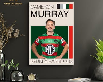 May include: A framed poster featuring Cameron Murray in a rugby jersey. The poster has a cream background with the name "CAMERON MURRAY" in bold black letters. The team name "SYDNEY RABBITOHS" is at the bottom. The jersey is green, red, and white.
