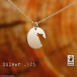 A silver necklace pendant with a silhouette of a wolf's head.