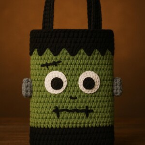 May include: A handmade crochet bag in the shape of Frankenstein's monster. The bag features a green body, black hair and accents, and white eyes. The bag has a handle and is perfect for Halloween.