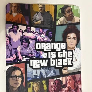 May include: A rectangular coaster featuring a collage of images from the television show "Orange is the New Black." The coaster has a colorful design with the show's title in bold, white letters.