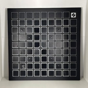 Könnte beinhalten: Ein schwarzes quadratisches Ziel mit einem weißen Gittermuster und einem kleinen weißen Diamanten in der oberen rechten Ecke.