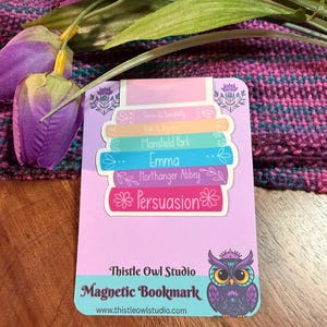 May include: A rectangular magnetic bookmark with a stack of colorful book spines featuring titles like "Sense & Sensibility" and "Persuasion." The bookmark has a purple owl illustration and the text "Thistle Owl Studio Magnetic Bookmark."