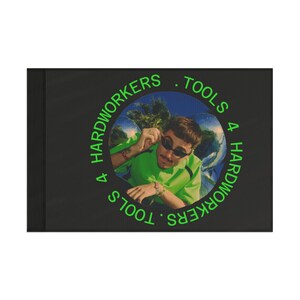 May include: A black rectangular item with a circular image of a person wearing sunglasses and a green shirt. The text "4 HARDWORKERS . TOOLS 4 HARDWORKERS" is in green around the image.