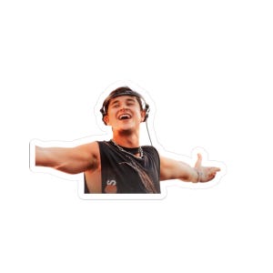 May include: A sticker featuring a smiling person wearing headphones and a black tank top with the letter "S" on it. The person has their arms outstretched, and a silver chain necklace is visible.