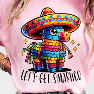 Puede incluir: Camiseta rosa con una piñata de dibujos animados que lleva un sombrero y el texto "Let's Get Smashed".