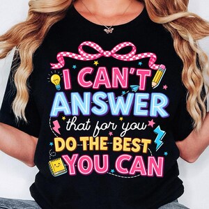Pode incluir: T-shirt preto com a frase colorida "I CAN'T ANSWER that for you DO THE BEST YOU CAN". O design inclui uma lâmpada, um lápis e estrelas.