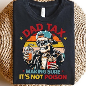 Könnte beinhalten: Schwarzes T-Shirt mit einer Grafik eines Skeletts mit Sonnenbrille und Kappe, das ein Getränk und Pommes hält. Der Text lautet "DAD TAX MAKING SURE IT'S NOT POISON" in Rot und Gelb.