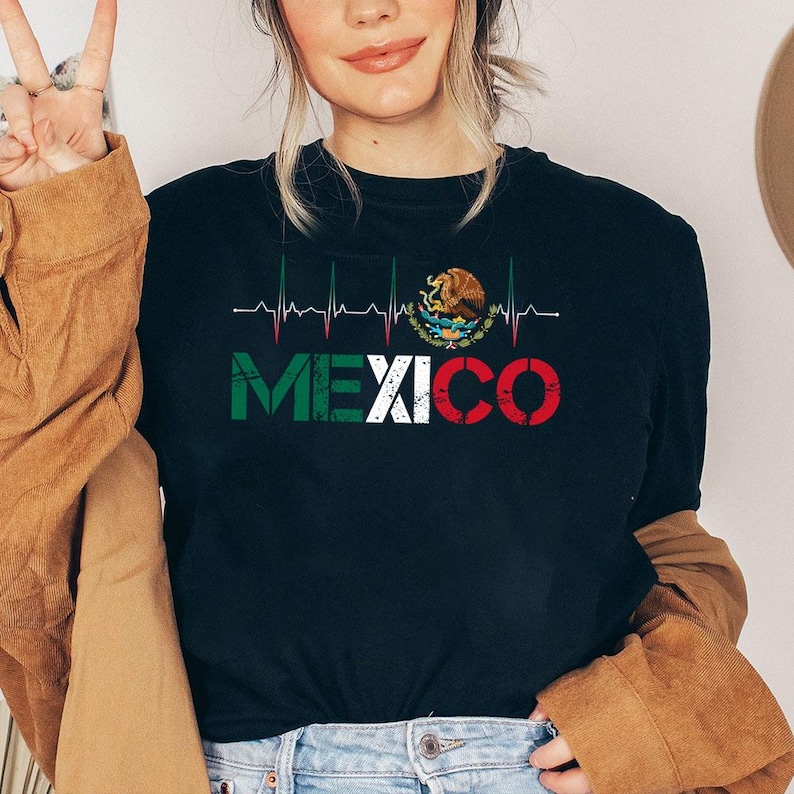 May include: Black t-shirt with the word "MEXICO" in green, white, and red, and a heartbeat line design. The shirt also features the Mexican coat of arms. A casual top for those who love Mexico.