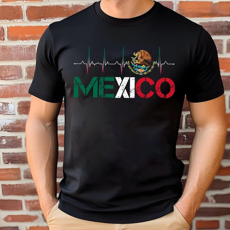 May include: Black t-shirt with the word "MEXICO" in the colours of the Mexican flag, with a heartbeat graphic above. The design includes the Mexican coat of arms. A casual, patriotic apparel item.