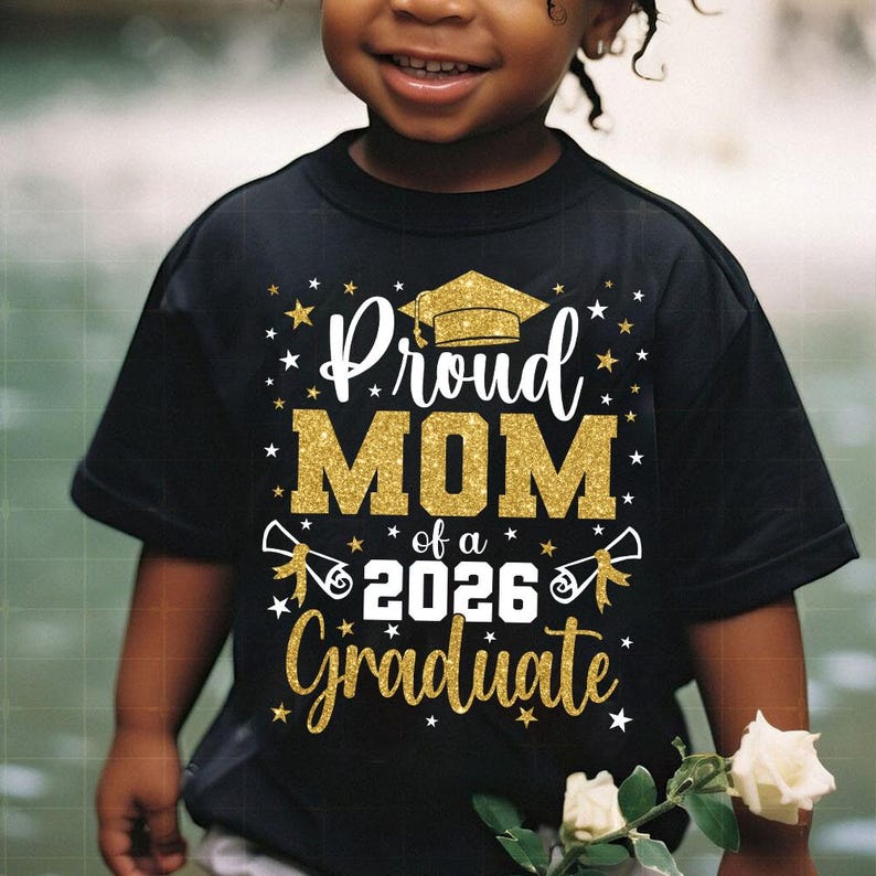 May include: Black t-shirt with gold glitter text that reads "Proud MOM of a 2026 Graduate." The design includes a graduation cap and stars. The shirt is worn by a child.