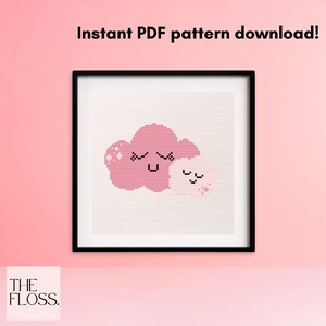 May include: A cross-stitch pattern featuring two cute clouds with smiling faces. The larger cloud is pink and the smaller cloud is white. The pattern is framed in a black frame and displayed against a pink background. The text "Instant PDF pattern download!" is displayed above the frame.