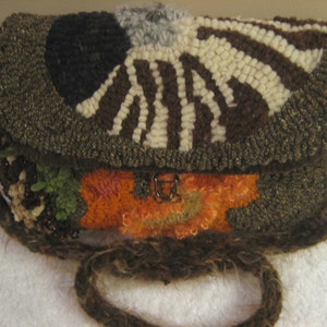 May include: A brown, white, and black crocheted handbag with a clasp closure. The bag has a long brown strap and is decorated with various colorful fabric scraps.