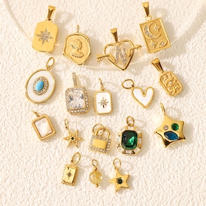 May include: A collection of gold-colored pendants with various designs, including stars, hearts, and geometric shapes. Some pendants feature gemstones, while others have intricate patterns. The pendants are displayed on a textured, off-white surface.