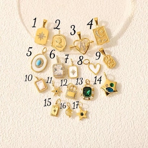 May include: A collection of gold-colored pendants with various designs, including stars, hearts, and geometric shapes. Some pendants feature gemstones and intricate detailing. The pendants are displayed on a cream-colored surface.