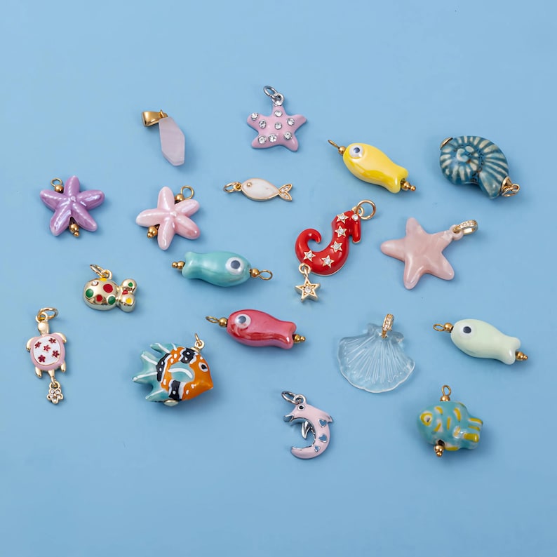 May include: A collection of colorful, nautical-themed charms in various shapes, including starfish, fish, and seahorses. The charms are in shades of pink, blue, yellow, and red, with gold-colored accents. The charms are designed for jewelry making.