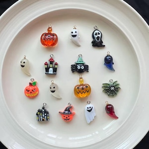 Può includere: Una collezione di ciondoli a tema Halloween in varie forme, tra cui zucche, fantasmi, ragni e una casa stregata. I ciondoli sono arancioni, neri, bianchi e verdi, con anelli dorati per il fissaggio a gioielli o lavori artigianali.
