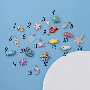 May include: A collection of colorful ocean-themed charms, including starfish, fish, seahorses, and shells. The charms are in various colors such as pink, blue, yellow, and red. Each charm has a small loop for attaching to jewelry or other crafts.
