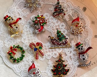 Peut inclure: Une collection de dix broches en métal sur le thème de Noël, comprenant un flocon de neige argenté, deux bonhommes de neige avec des écharpes rouges, deux visages de Père Noël, deux sapins décorés, une couronne, un traîneau et un sucre d'orge.
